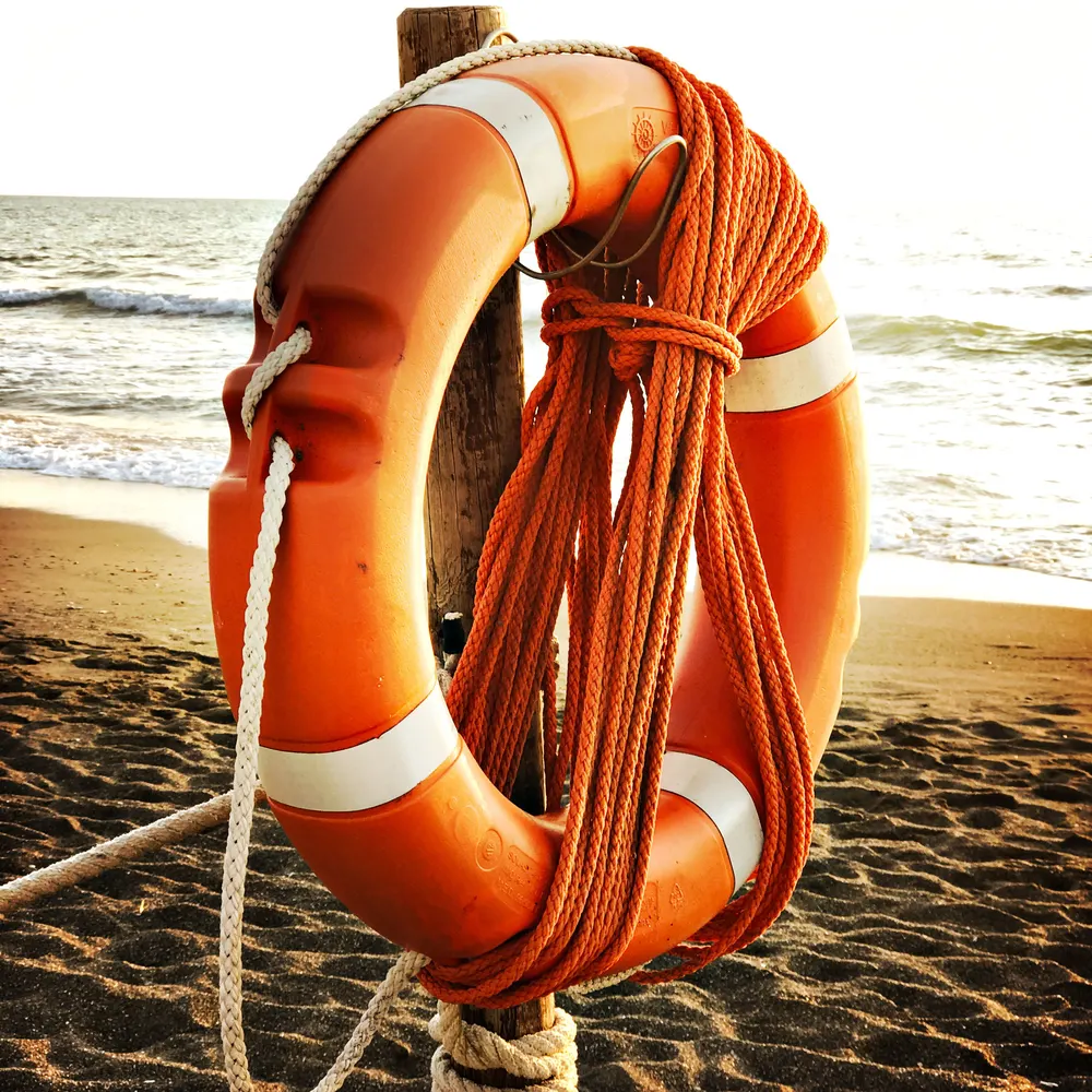 Orangefarbener Rettungsring am Strand